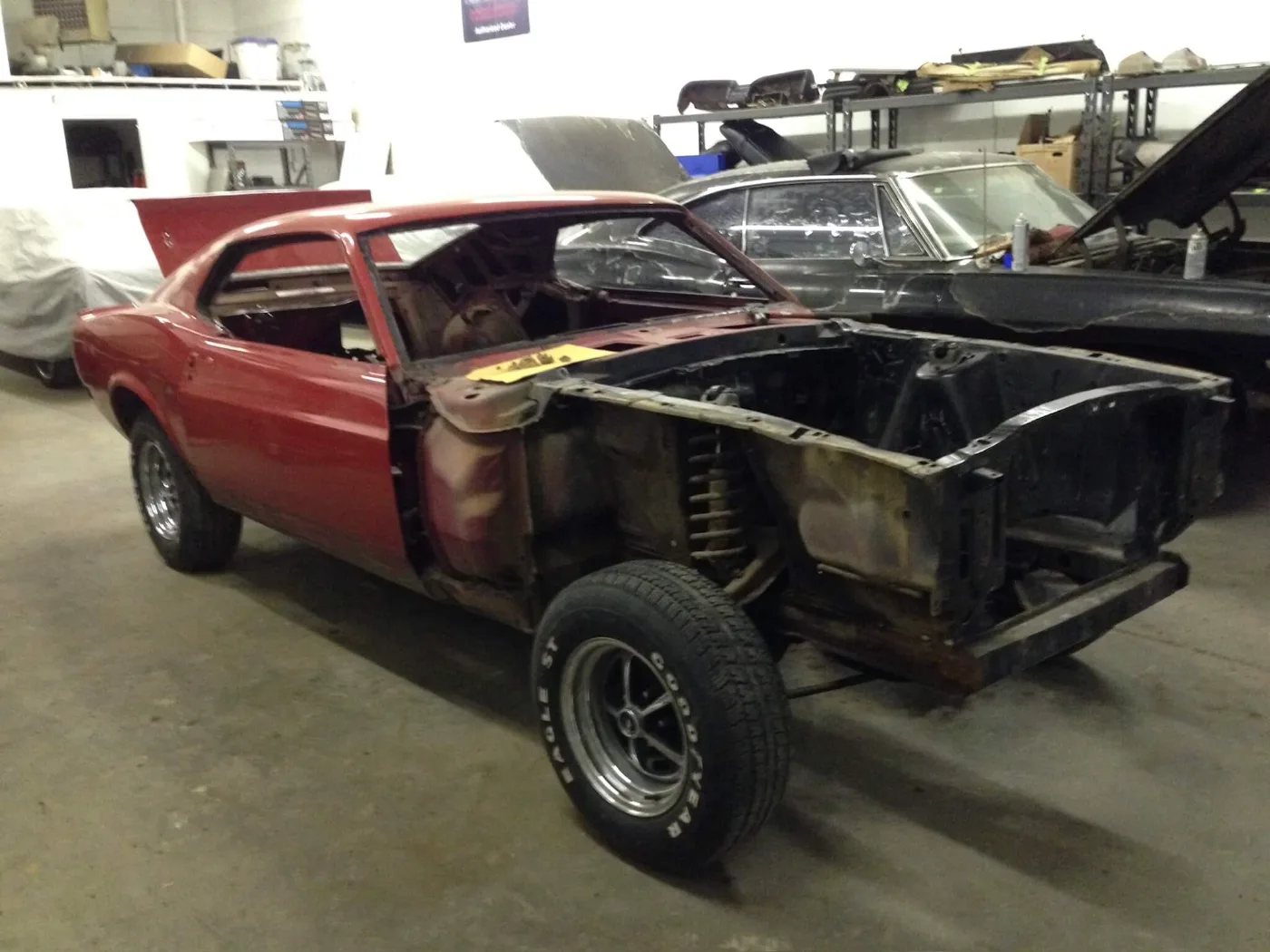 Red Ford Mustang fastback stripped to bare metal at the front end